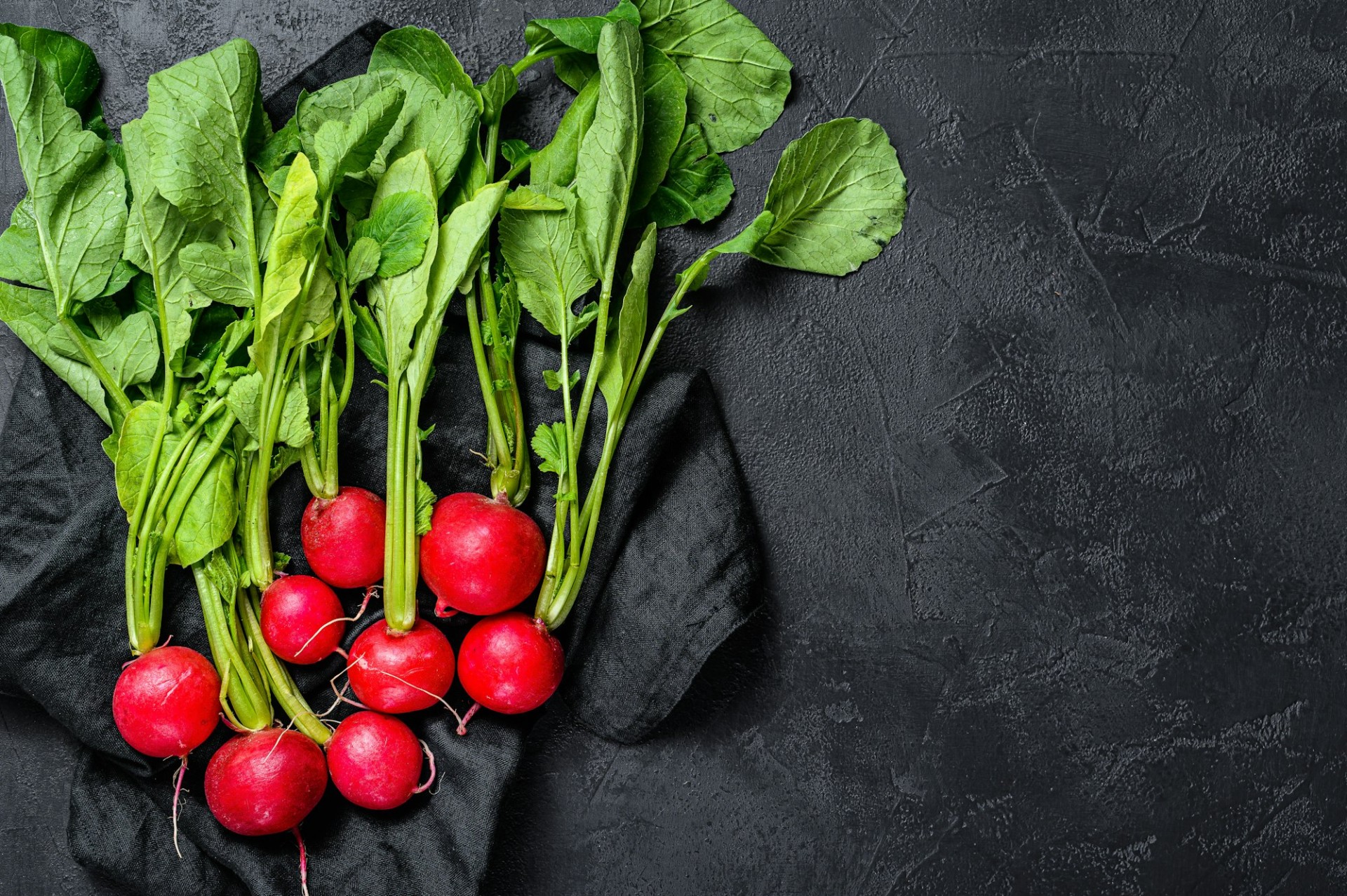 large bunch of fresh radish. Black background. Top view